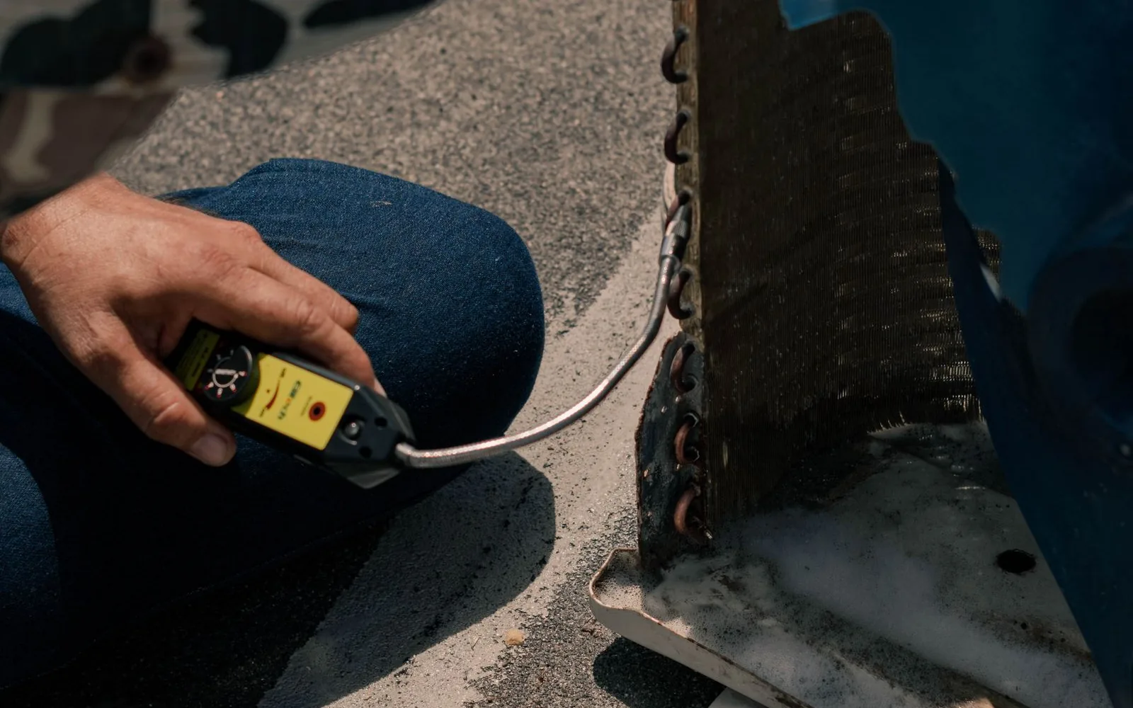 Technician using a measuring tool beside exposed air conditioning coils